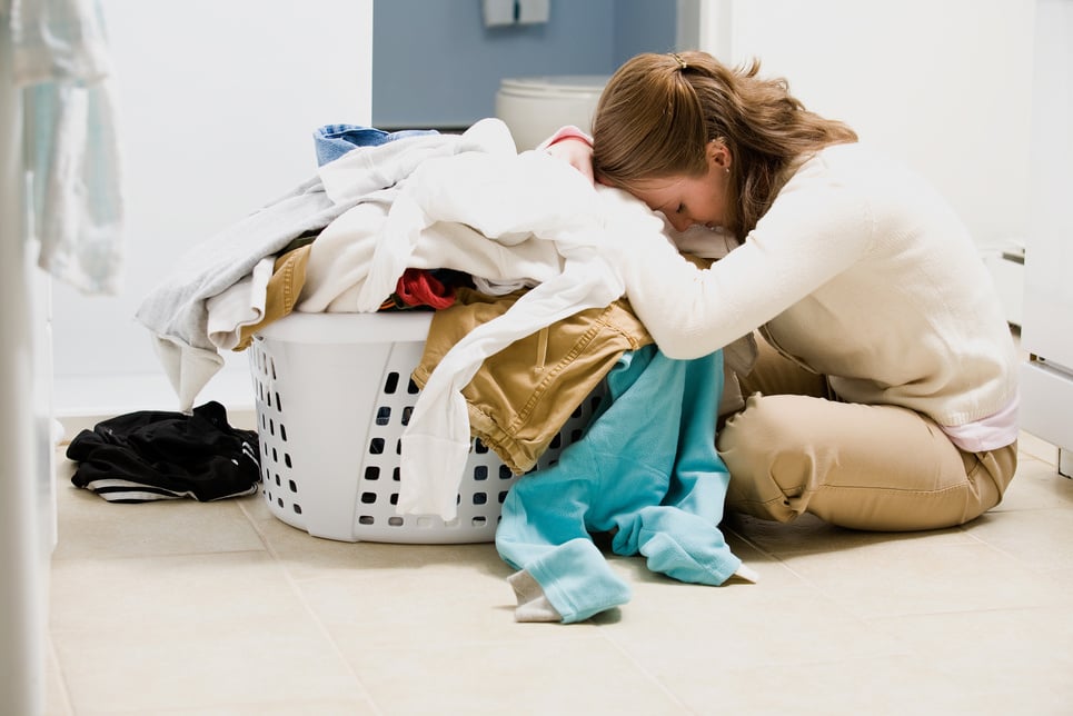 Overwhelmed woman facing basket of laundry